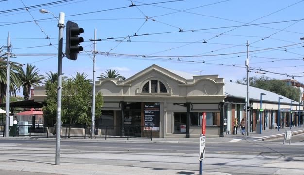 Image shows the exterior of the railway station from across a busy road. 